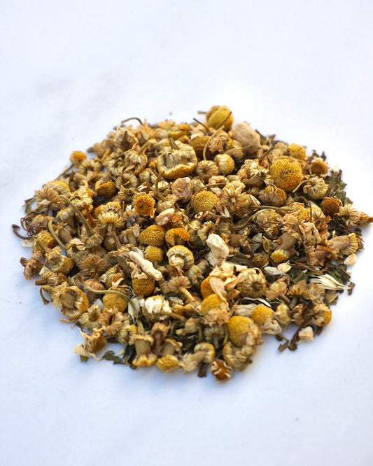 Image of Sunny hills tea soothing, ginger, chamomile, spearmint blend in loose leaf form. showing the full chamomile flower, dried peppermint leaves, and organic dried ginger granules.